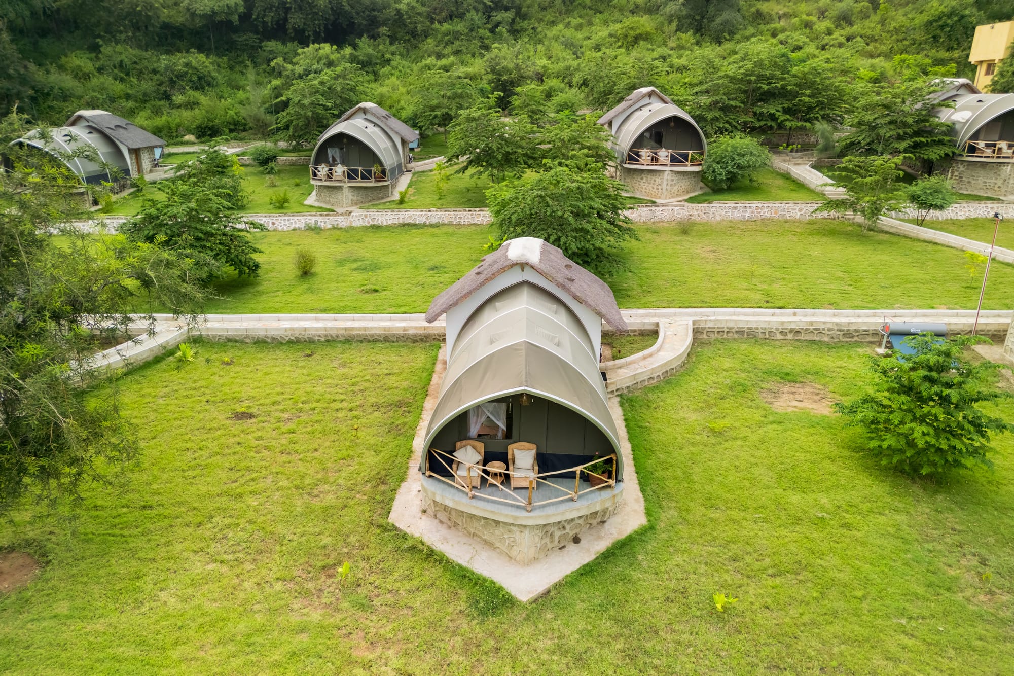 Arched tented suites with private verandas, seen from above on mown lawns